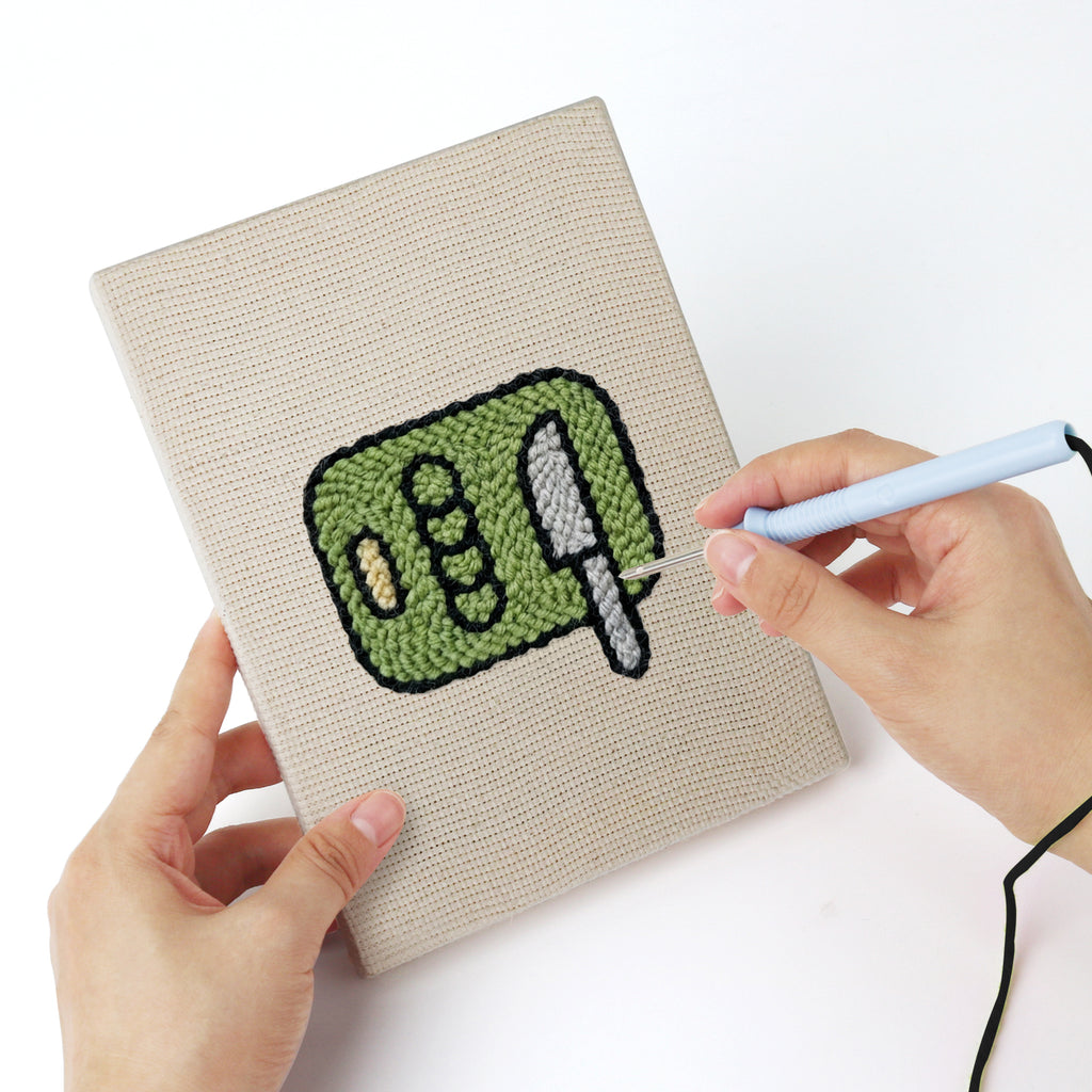 Punching a Backyard Burger Cook mini canvas with the punch needle