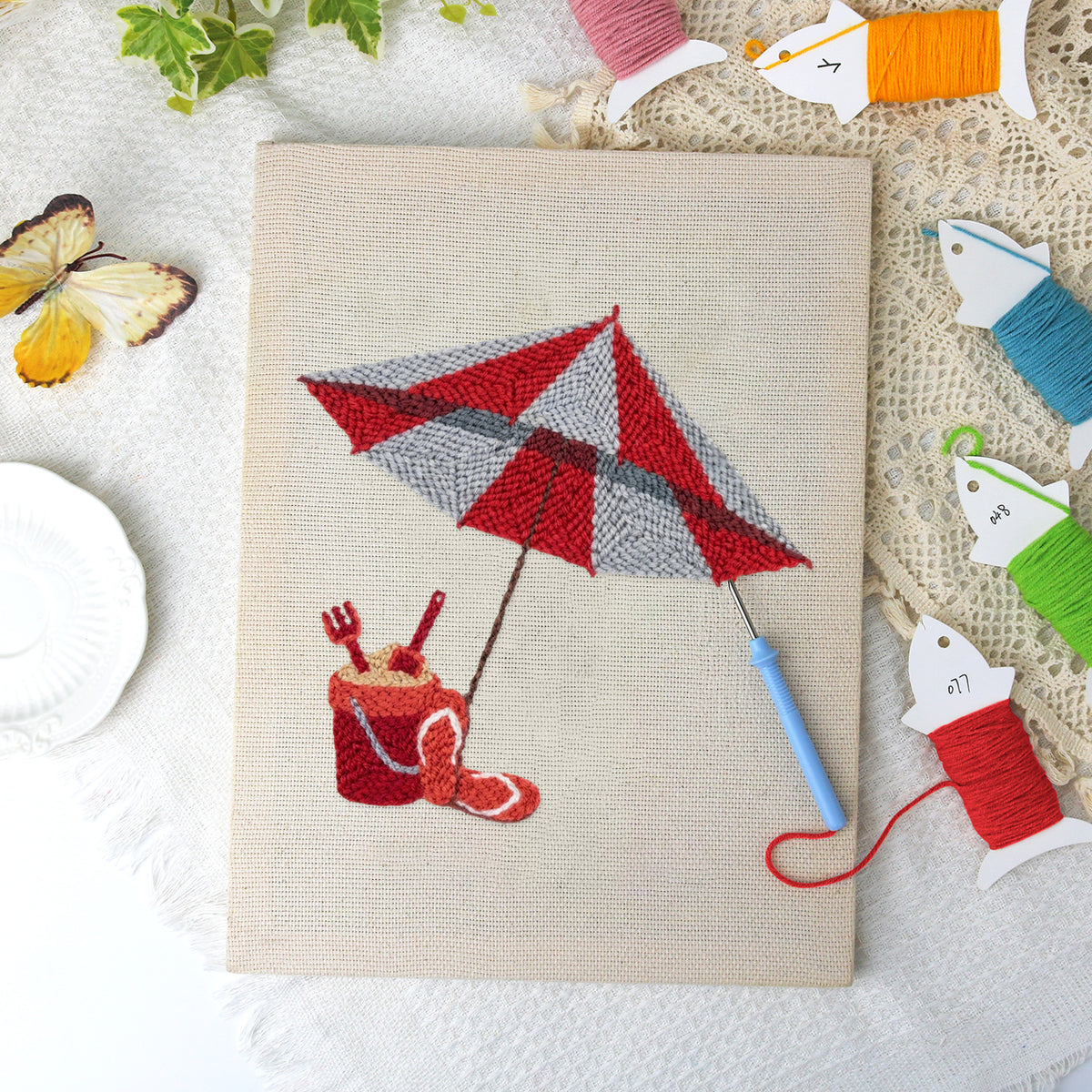Beach Umbrella Day canvas before and after punching, with the threads and tools