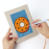Punching a Blue Donut Duo mini canvas with the punch needle