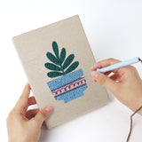 Punching a Blue Pot Houseplants mini canvas with the punch needle