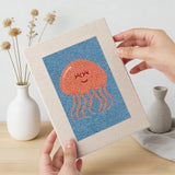 Hand holding a finished Blue Sea Friends mini canvas