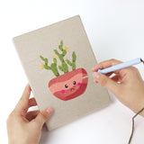 Punching a Blushing Coral Pots mini canvas with the punch needle