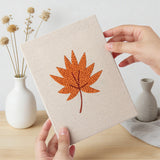 Hand holding a finished Burnt Orange Leaves mini canvas