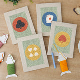 The four finished Card Suit Circles mini canvases laid out on a table