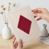 Hand holding a finished Card Suits mini canvas