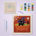 Cat in a Cauldron Bath canvas before and after punching, with the threads and tools