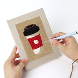 Punching a Coffee Shop Cups mini canvas with the punch needle