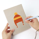 Punching a Earflap Winter Hats mini canvas with the punch needle