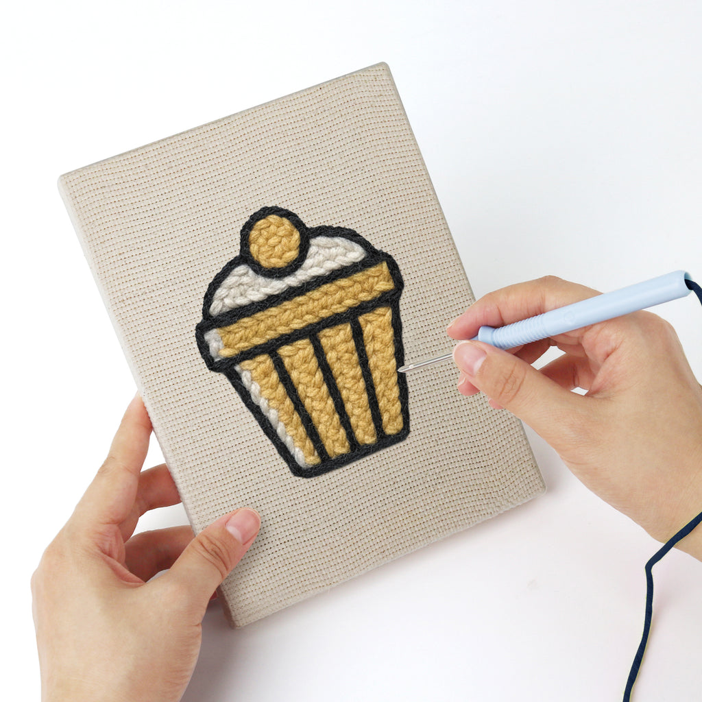 Punching a Golden Popcorn Bucket mini canvas with the punch needle