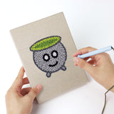 Punching a Green Skull Cauldron mini canvas with the punch needle