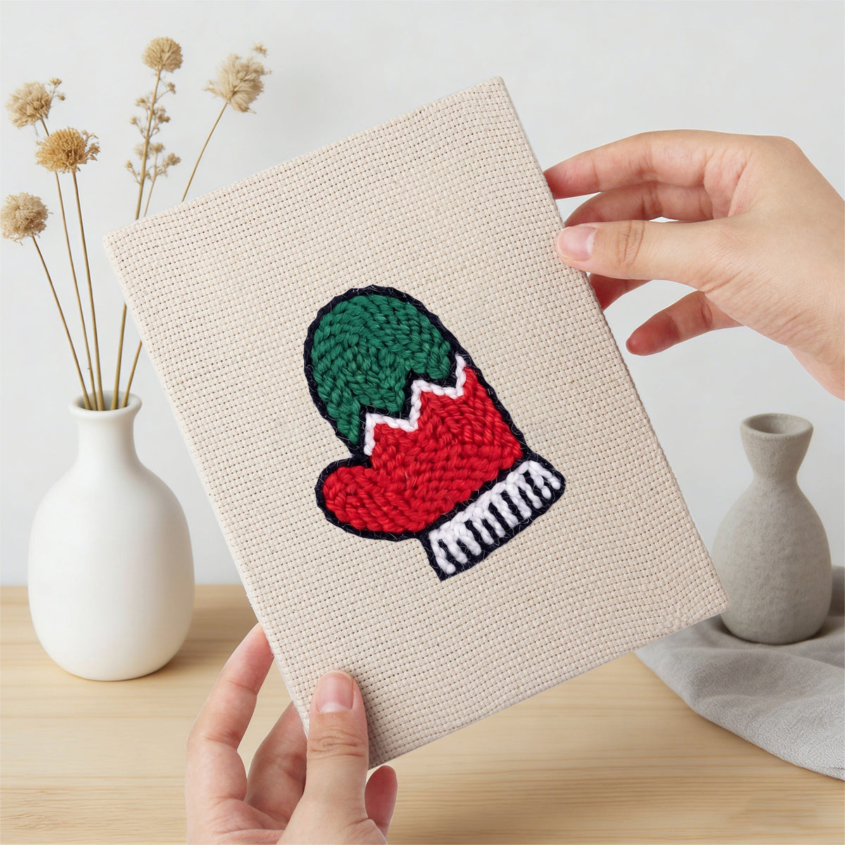Hand holding a finished Holly and Mitten mini canvas
