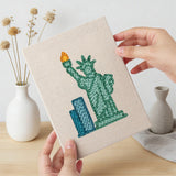 Hand holding a finished Landmark Postcards mini canvas