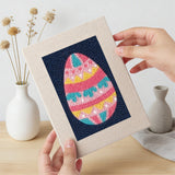 Hand holding a finished Navy Easter Eggs mini canvas