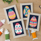 The four finished Navy Easter Eggs mini canvases laid out on a table