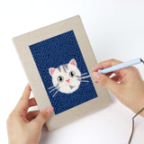 Punching a Navy Teal Cats mini canvas with the punch needle