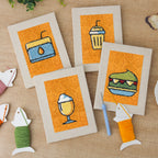 The four finished Orange Drink Stand mini canvases laid out on a table