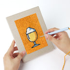 Punching a Orange Drink Stand mini canvas with the punch needle