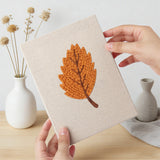 Hand holding a finished Orange Maple Leaves mini canvas