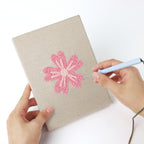 Punching a Pink Blossom Heads mini canvas with the punch needle