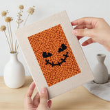 Hand holding a finished Pumpkin Grins mini canvas