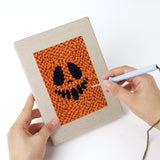 Punching a Pumpkin Grins mini canvas with the punch needle