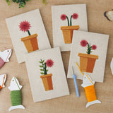 The four finished Red Daisy Pots mini canvases laid out on a table