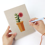 Punching a Red Daisy Pots mini canvas with the punch needle