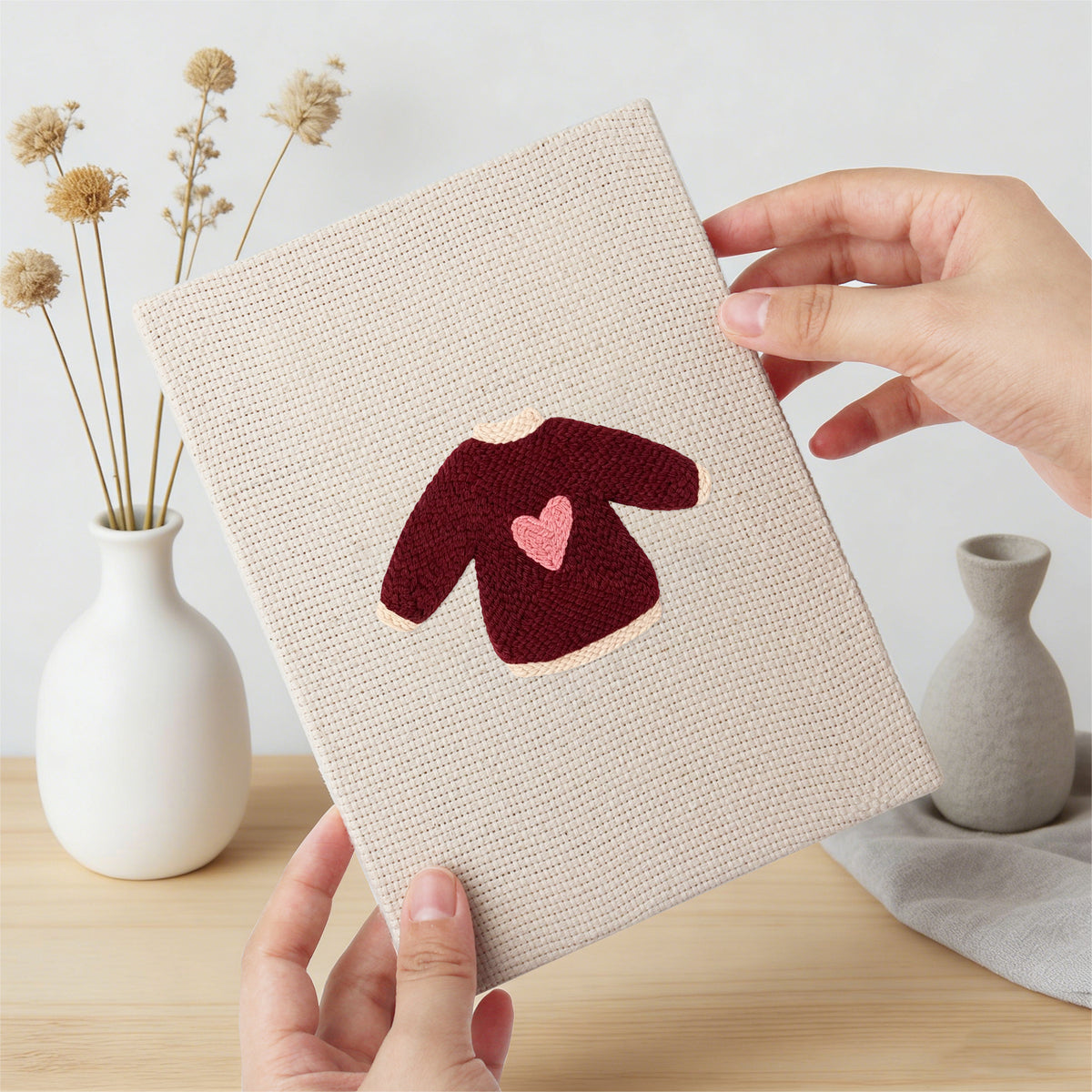 Hand holding a finished Red Heart Sweaters mini canvas