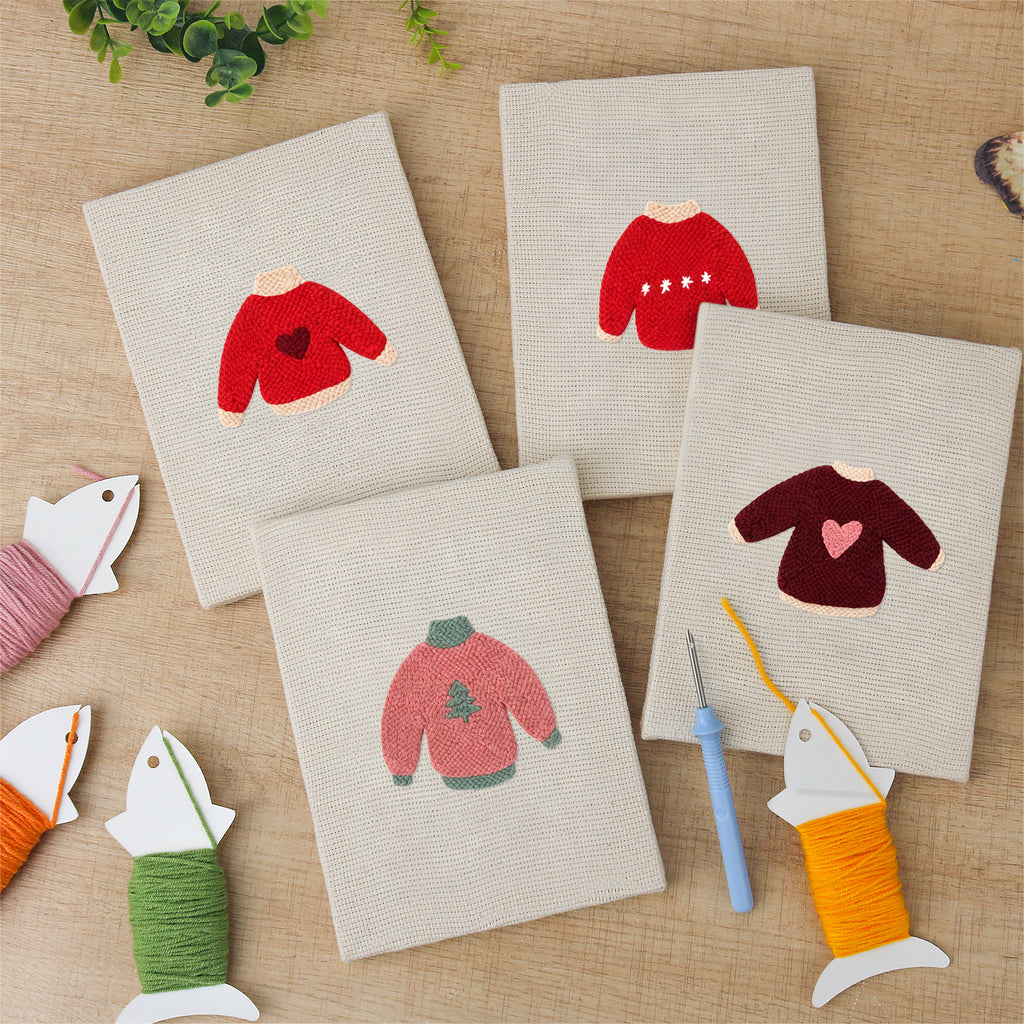 The four finished Red Heart Sweaters mini canvases laid out on a table