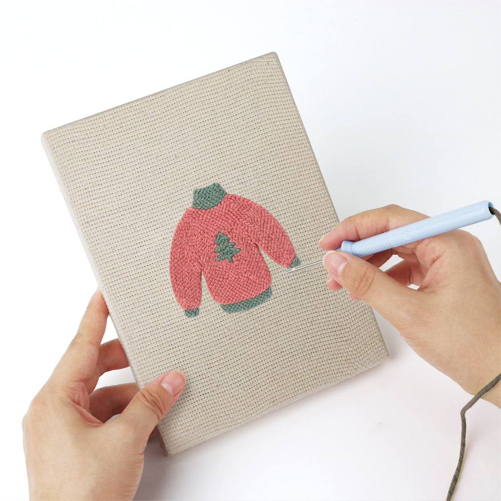 Punching a Red Heart Sweaters mini canvas with the punch needle