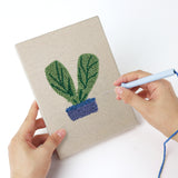 Punching a Red Pot Posies mini canvas with the punch needle