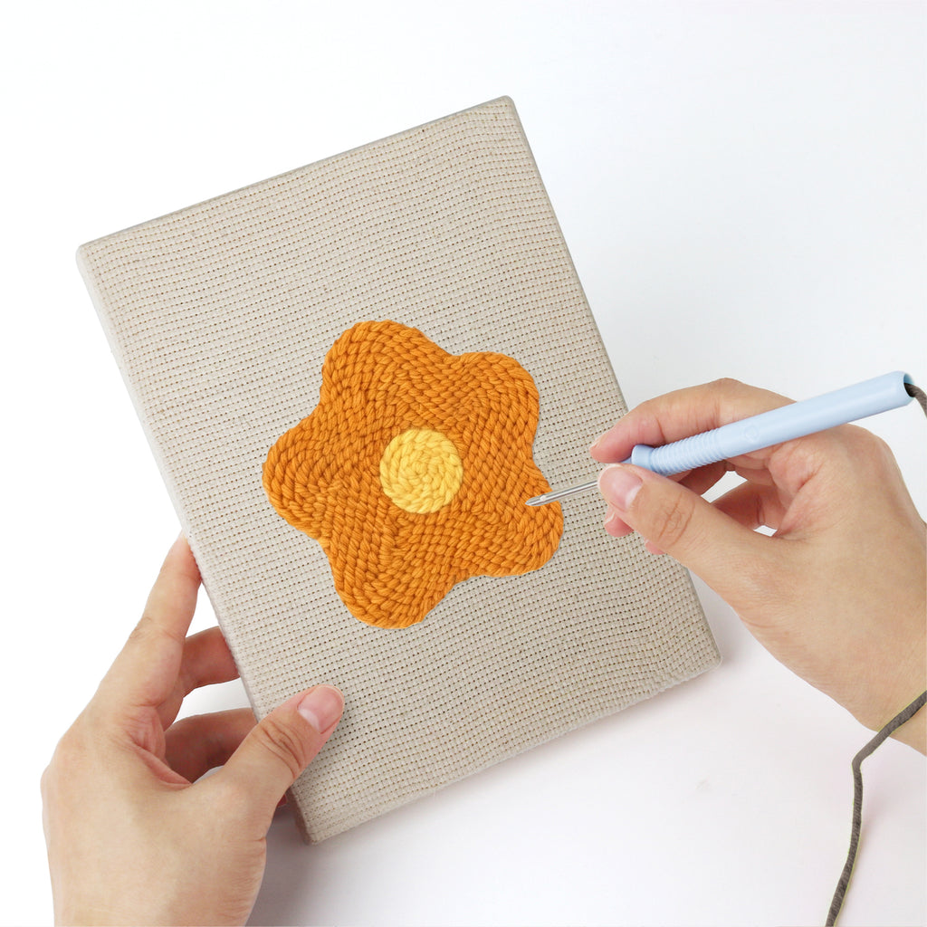 Punching a Retro Flower Heads mini canvas with the punch needle