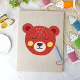 Rosy Cheek Bear canvas before and after punching, with the threads and tools