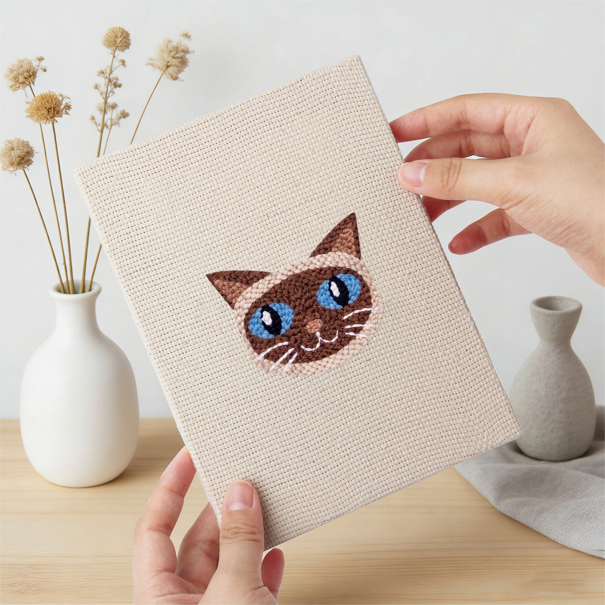 Hand holding a finished Siamese and Tuxedo mini canvas