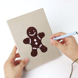 Punching a Snowy Cabin mini canvas with the punch needle