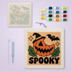 Spooky Pumpkin Grin canvas before and after punching, with the threads and tools