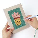 Punching a Teal Coral Reef mini canvas with the punch needle