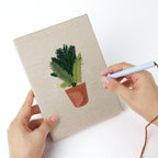 Punching a Teal Pot Greens mini canvas with the punch needle