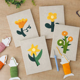 The four finished Yellow Folk Flowers mini canvases laid out on a table