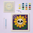 Yellow Skull Daisy canvas before and after punching, with the threads and tools